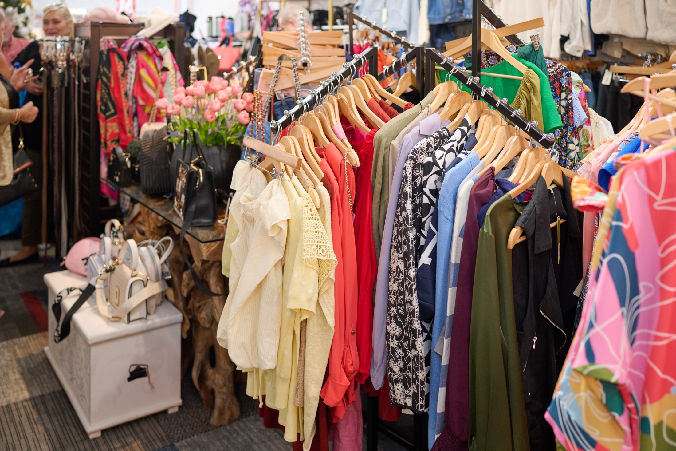 Curated women's dresses and blouses on a brass rack